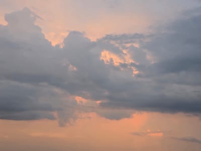 The image shows a sky filled with clouds during either sunrise or sunset. The clouds are a mixture of dark gray and lighter, pinkish-orange hues, suggesting the presence of sunlight filtering through them. There are no discernible landmarks or structures visible that would indicate a specific location within the city of Širvintos, Lithuania. The scene is entirely focused on the atmospheric conditions of the sky.