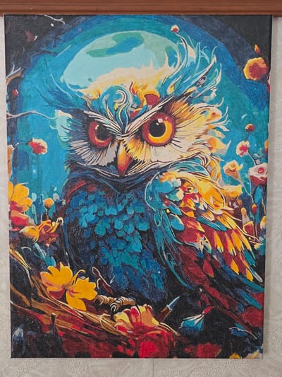 This is a painting of an owl in a stylized, colorful forest. The owl is the central subject, depicted in vibrant blues, yellows, and reds, with large, striking orange and red eyes. Its feathers are rendered with dynamic brushstrokes, giving a sense of movement and texture. The background is a dark, abstract forest scene, with splashes of color representing foliage and perhaps flowers in shades of blue, red, yellow, and orange. The overall impression is one of intensity and wild beauty, with a slightly surreal or dreamlike quality due to the bold color choices and abstract rendering of the environment. There is no visible text in the image. The setting appears to be a natural environment, though the specific location cues are not clear enough to pinpoint Serebriansk, Kazakhstan beyond the provided context. The time of day and weather are not discernible from the painting itself. The emotions conveyed are a sense of power and mystery associated with the owl.