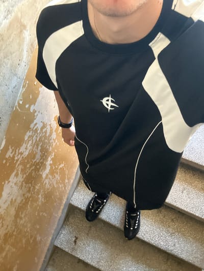 A high-angle shot shows a person standing on what appears to be a set of concrete stairs, possibly indoors. The person is wearing black clothing with white accents and dark shoes. The environment consists of the stairs and a wall with a mottled or discolored surface. There is no specific indication of Elhovo, Bulgaria in the image.