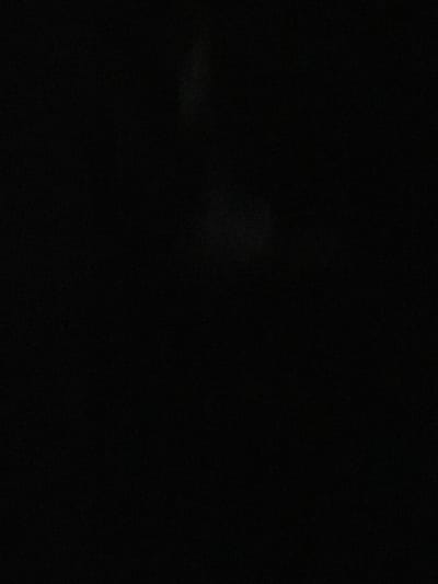 The image depicts a completely black scene with some subtle, faint white and grey speckling throughout. There are no discernible objects, people, actions, interactions, or environmental details visible. The image is entirely abstract due to the lack of light and content. There is no information available within the image to identify its location in Malete, Nigeria.