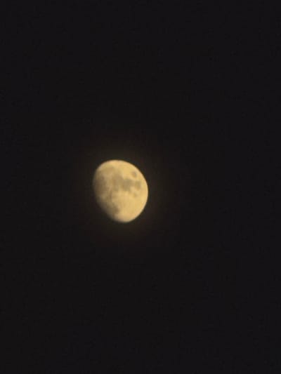 This is a photograph of the moon against a dark night sky. The moon is partially illuminated, showing craters and surface details. It is a cool, clear night, typical of the region. The image appears to have been taken with a moderate zoom, bringing the moon into focus against the vast expanse of space. There are no people or man-made objects visible in the frame. The scene is serene and focuses entirely on the celestial body. The setting is likely outdoors, in an area with minimal light pollution to allow for a clear view of the moon.