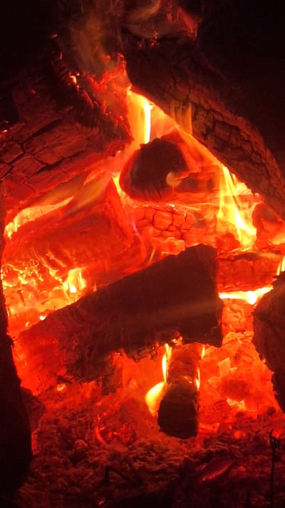 The media file is a close-up shot of a fire burning in what appears to be a fireplace or bonfire. The subjects are logs of wood that are actively burning, glowing with intense shades of orange, yellow, and red. The flames are visible, creating a dynamic and fiery scene. The textures of the burning wood are detailed, showing cracks and charring. The background is dark, emphasizing the brilliance of the fire.
The activity taking place is the combustion of wood, producing heat and light. The scene is visually striking due to the vibrant colors of the fire and the contrast with the darkness. There are no people visible in the image. The lighting is entirely from the fire, creating a warm and intense atmosphere. No time of day, weather, or specific location cues are discernible beyond the presence of a fire. No text is visible in the image.
