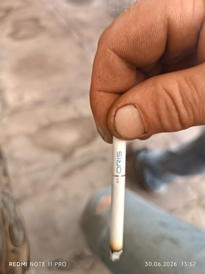 A close-up shot shows a hand holding a white cigarette with the brand name "ORIS" printed in blue. The cigarette appears to be lit, with ash at the tip. The background is blurred, showing a light-colored, textured surface, possibly a floor or table. In the bottom left corner, the text "REDMI NOTE 11 PRO" is visible, indicating the phone model used for the photograph. The bottom right corner displays a date and time stamp: "30.06.2026 13:57". The image does not contain any information or visual cues that would allow for the identification of the city of Petrovka, Kyrgyzstan, or any specific location within it.