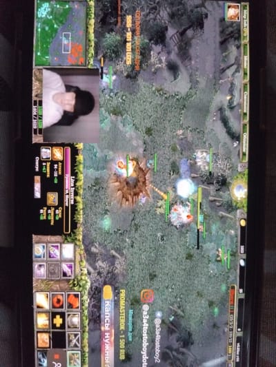 The image shows a screen capture of a computer screen displaying the game Dota 1. A male individual is visible in a webcam inset, likely streaming the game. The game interface shows the player is playing Lina Inverse, level 18, with associated stats like attack, defense, strength, agility, and intelligence. In-game currency is shown as 1963. Chat/donation messages appear on the screen, including "PROMASTEROK - 1500 RUB" and social media handles "@a3a4tostoboy2" and "@a3a4tostoboydota". The game interface is in Russian. The location is not indicated in the image.