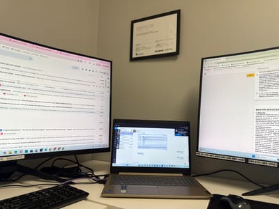 An overhead view captures a multi-monitor computer workstation in what appears to be an office or home office setting. Two large external monitors flank a laptop, all displaying active work. A black keyboard and a Logitech mouse sit on the dark desk surface, with cables visible behind them.

The left monitor displays an email client, likely Google Workspace, showing numerous emails related to services, payments, and inspections. Notable email subjects include "Mills Law Group" with a $3068.01 invoice, "Marietta 30062 - Sewer Camera Inspection," and multiple Zelle payments from individuals like Darwin Diocares ($1495.00) and Grace Mallard ($385.00). There are also emails regarding "Certificate of Insurance for American Rooter Services Inc." and "Progress Residential - T90 Service Scorecard." Timestamps on the emails range from 9:09 AM to 10:34 AM, with dates in late May and early June 2026. A phone number "FL 813 725 4922" is partially visible at the bottom.

The laptop screen shows a communication application, possibly Microsoft Teams, with a chat window featuring "Gary 103 103." A chat message provides instructions: "Please find the information in these 3 emails. Just reply and send them the exact same thing. Thank you!"

The right monitor displays a web page from app.pandadoc.com, presenting a "Florida Plumbing and Leak Detection LLC - Contractor Enrollment Packet" with detailed legal text under sections like "MASTER SERVICES," "3. Materials," and "4. Professionalism." A small weather widget at the bottom indicates "74°F Partly sunny" and the current time as "10:35 AM" on "6/2/2026." Below this, several phone numbers are visible: "ARS RC 678-641-4375 ARS 678-883-6329 GRS 470-454-5051."

Above the left monitor, a framed "CERTIFICATE OF COMPLETION" is mounted on a light-colored wall. It signifies an "Accelerated HR Management Certificate Program" from "Graceland" and "SkillPath," dated "4/20/2026 - 4/24/2026." The overall scene suggests an individual actively managing administrative, communication, and document-related tasks, likely within the property services or contracting industry across different states (Florida and Georgia).