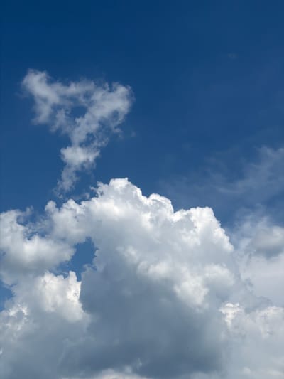 The media file displays a dynamic sky with a gradient of deep blue transitioning to lighter shades, interspersed with various cloud formations. Dominating the right side of the frame is a large, fluffy white cumulus cloud with distinct textures and shadows, suggesting depth and volume. To the left, a scattering of smaller, wispy clouds drift across the blue expanse, with one larger, more defined cloud formation in the lower left quadrant. The interplay of light and shadow across the clouds indicates a bright, possibly sunny day, with the sun likely positioned out of frame or obscured by clouds. There are no visible people, objects, or text. The scene evokes a sense of open space and natural beauty, typical of an outdoor environment, possibly a rural or suburban landscape given the clear sky and cloud formations. The weather appears to be fair but with considerable cloud cover, suggesting it might be daytime, possibly late morning or early afternoon, when sunlight is strong. The location context of Palilula Urban Municipality, Serbia, implies this is an outdoor scene viewed from ground level, looking upwards.