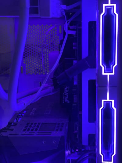 The image shows the interior of a computer case with blue LED lighting. A graphics card, identified by the "GIGABYTE" and "FUR" branding, is visible. Several cables and components, including what appears to be a RAM stick labeled "DDR5," are also present. The computer case has a perforated design, and there is a visible dust buildup on some components. The image is taken from a close-up perspective, with the computer's internal components filling the frame. There is no indication of the city of Grozny, Russia, or any other geographical location in the image.