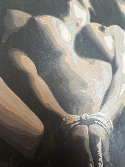 A close-up section of a painting on canvas depicts a human figure, possibly male, bound with rope. The figure's torso, arms, and possibly legs are visible, rendered in layered shades of white, grey, and brown. The rope appears tied around the figure's wrists. The background is dark, seemingly black. The painting style is characterized by distinct, flat areas of color, creating a stylized or graphic effect. The location is not evident from the image.