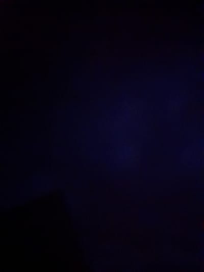 The image is an extremely dark, almost entirely black and deep blue abstract photograph. There is a subtle gradient from near black on the left to a deep, slightly textured blue on the right. At the very bottom left corner, a faint, dark, silhouetted shape is discernible, possibly indicating a portion of a structure or object casting a shadow. The image is devoid of any discernible details related to the city of Kliushnykivka, Ukraine, or any specific subjects, actions, or interactions.