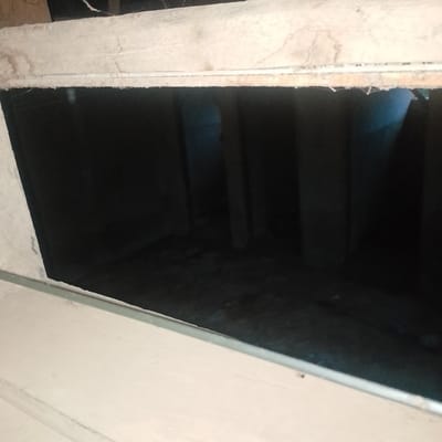 The image depicts a dark, unfinished interior space, possibly a crawl space or a room under construction. The visible area shows rough, unpainted walls and what appears to be exposed insulation along the top edge of an opening. The floor is uneven and dark, with some debris visible. The lighting is dim, casting long shadows and obscuring details within the space. The location in Ogbomosho, Nigeria, is not visually evident from the provided image.