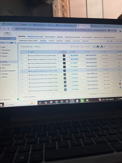 The image displays a laptop screen showing a social media management platform, likely for marketing. The platform is titled "Omni Online" and features a "Planificador de redes sociales" (social media planner) interface. The screen shows a list of scheduled and published social media posts with dates, content summaries, and statuses. The background of the image reveals a dark keyboard, suggesting the laptop is in use in a dimly lit environment. The weather widget in the bottom right corner of the screen indicates "22°C Parc. soleado," meaning "22°C Sunny Park." There are no indications of the specific location within San Luis, Peru, in the image.
