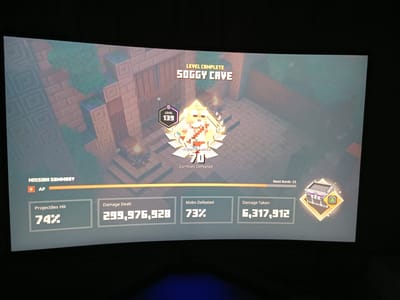 The image displays a "Level Complete" screen from the game Minecraft Dungeons, showing the player has finished the "Soggy Cave" level. The player's level is 139, and they have defeated 70 zombies. Mission summary statistics include: 74% Projectiles Hit, 299,976,928 Damage Dealt, 73% Mobs Defeated, and 6,317,912 Damage Taken. The next rank is 33, indicated next to a treasure chest icon. The background is a pixelated in-game environment. There are no people, objects, or actions outside of the game's interface. There is no information or context within the image that connects it to the city of Lügde, Germany.