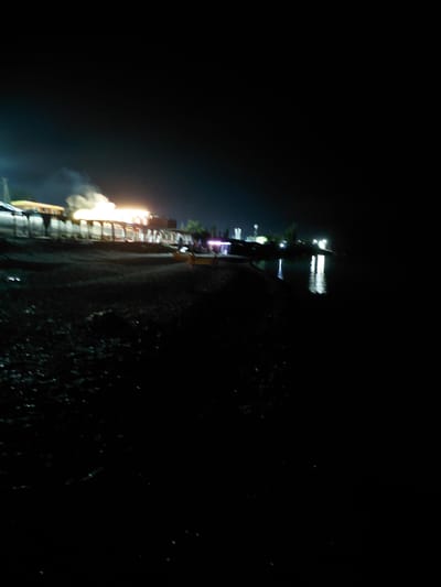 This media file depicts a night scene, possibly fireworks or a celebration, in Akshy, Kazakhstan. The primary subject is a vertical structure, possibly a building or a temporary stage, illuminated by bright lights and emitting a smoky haze. The lights appear to be a mix of white and pink, with some parts of the structure being more intensely lit than others. The overall image is dark, suggesting it was taken at night, and the lighting implies an active event.
The scene is set against a dark background, with some indistinct lights and reflections visible on the right side, hinting at a water body or a reflection in the environment. The quality of the image is somewhat blurred, possibly due to movement or low light conditions. There are no discernible people in the image, but the presence of illumination and activity suggests a gathering or event.
Notable details include the bright, glowing lights and the smoky effervescence emanating from the structure. The time of day is clearly night. The location cues are limited to the name Akshy, Kazakhstan. There is no visible text in the image. The atmosphere conveyed is one of spectacle and perhaps excitement, given the nature of the light display. The image captures a moment of visual intensity within a dark setting.