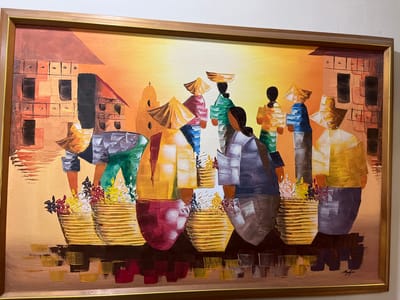 This is an oil painting on canvas depicting a group of people, likely vendors, in an outdoor marketplace setting. The figures are rendered in a stylized, somewhat abstract manner, with thick impasto brushstrokes giving them a textured appearance. Many of the individuals wear conical hats and traditional clothing in vibrant colors such as yellow, green, red, and blue.

The people are shown carrying baskets, some filled with colorful flowers. The background features rudimentary depictions of buildings with distinct architectural features like windows and roofs, suggesting an urban or semi-urban environment. The overall color palette is warm, with dominant oranges, yellows, and browns, hinting at a sunny day, possibly during sunset or sunrise due to the gradient of light. The reflections of the figures and baskets in what appears to be water or a wet surface below add a layer of depth to the composition.

There is a signature in the lower right corner of the painting. The scene evokes a sense of daily life and commerce in a tropical location. Given the context of Quezon City, Philippines, the painting likely represents a market scene or a gathering of local people engaged in trade. There are no explicit clues about specific weather conditions beyond the warm lighting. The emotion conveyed is one of industriousness and community.
