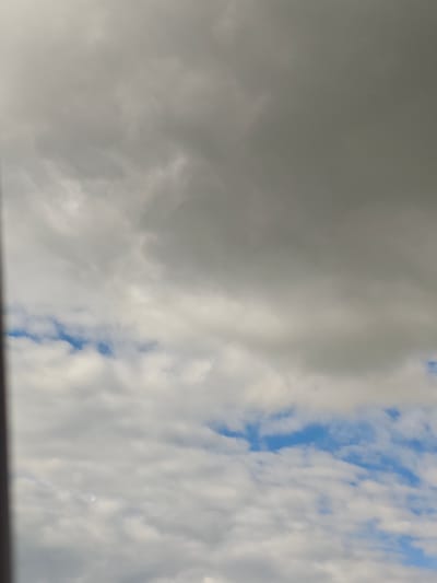 The image displays a sky with varied cloud formations. The upper portion of the image is dominated by dark, heavy clouds, suggesting overcast conditions. Towards the middle and lower sections, lighter, more diffused clouds are visible, interspersed with patches of blue sky. The lighting indicates it is daytime. There are no discernible landmarks or specific features that would allow for identification of a location within Gubithsky Selsovet, Belarus. The image does not contain any people, subjects, objects, or actions.