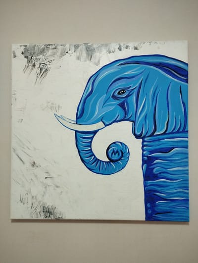 An acrylic painting of a blue elephant's head and trunk is displayed on a wall. The elephant is depicted in profile, facing left. Its trunk is curled inwards, and it has a single tusk. The background is white with streaks of gray and black paint, giving it a textured appearance. The painting is square-shaped and mounted on a light-colored wall. There is no information available about its location in Korolyov, Russia.