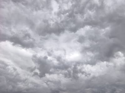The image is of a sky filled with dense, grey clouds. The clouds vary in shade, with some being lighter grey and others darker, indicating different depths and densities. There is no visible land or horizon, focusing entirely on the overhead cloud formation. There are no people, objects, or subjects apart from the clouds. It is not possible to tell if the image was taken in Jezreel Valley Regional Council, Israel or not.