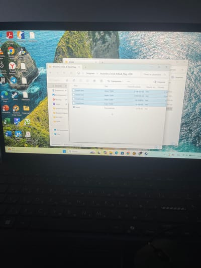 The image shows a laptop screen displaying a file explorer window open to the "Assassins_Creed_4_Black_Flag_v1.08" folder, located within the "Загрузки" (Downloads) directory. The folder contains several files with the ".dxn" extension (Data01.dxn, Data02.dxn, Data03.dxn, Data04.dxn) and a "Setup" application. The file sizes range from 4.739 KB to 2.548.831 KB.
The desktop background features a scenic view of a rocky island with lush greenery, partially submerged in a calm blue ocean under a clear sky. Several application icons are visible on the desktop, including Adobe Acrobat, Google Chrome, Steam, Microsoft Edge, and various other programs.
The lower portion of the image shows the laptop's keyboard, which is dark and appears to have Cyrillic characters on some keys. The operating system's taskbar is partially visible at the bottom, showing the time as 16°C, weather information, and icons for engagement, Wi-Fi, and battery status.
There is no visible information in the image to indicate the location of Sosnovka, Russia.