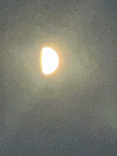 An illuminated, semi-circular object, appearing to be a light source, is visible against a textured, mottled gray background. The background exhibits a consistent, granular pattern throughout the image, suggesting a surface such as concrete or a textured wall. The light source is bright and emits a yellowish-white glow, with a subtle halo effect. The object is positioned in the upper left quadrant of the frame. No other objects or individuals are discernible. The scene lacks specific environmental indicators to pinpoint its exact location within Longpont-sur-Orge, France.