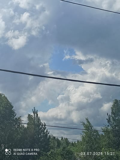 The image shows a cloudy sky with a clear patch of blue. Below the sky, there are trees and a power line. The bottom left corner of the image contains text that reads "REDMI NOTE 8 PRO AI QUAD CAMERA". The bottom right corner has a timestamp "03.07.2026 15:21". The scene appears to be outdoors, possibly in a natural or suburban environment given the presence of trees. The location is identified as Sovetskiy, Russia.