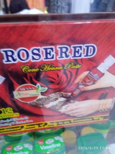 The image shows a close-up of a product box with the text "ROSERED" and "Cone Henna Paste" printed on it. There is a graphic of a red rose and a hand with henna designs. Below this, there is text that appears to be a product description, including the number "12" and the word "Sones." The bottom of the image shows several green containers, one of which has the label "Vaseline" visible. A timestamp, "2026/6/29 11:44," is present in the lower right corner. The overall scene appears to be a retail display or a close-up product shot, possibly in a store. There is no visible indication of the city of Ak-Suu, Kyrgyzstan.