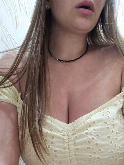 The media file is a close-up, rotated image of a person lying down, with their head tilted back. The subject has long, light brown hair that is spread out around their head and shoulders. They are wearing a light yellow garment with an eyelet pattern and a black beaded necklace. Part of their chest and décolletage is visible, as is their mouth. The background appears to be a textured, white surface, possibly a tiled floor or a bed. The lighting suggests an indoor setting during the daytime. There is no visible text in the image. The image does not provide sufficient information to determine the activity or event taking place, nor specific emotional cues beyond what might be inferred from the pose. The location context of Petropavlivska Borshchahivka, Ukraine, is provided externally and cannot be deduced from the visual content of the image itself.