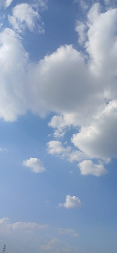 This media file depicts a sky with scattered white clouds against a bright blue backdrop. The clouds vary in size and density, with some appearing as large, billowy masses and others as smaller, wispy formations. The scene suggests an outdoor setting, likely during daytime, given the clear blue sky and the quality of light. There are no visible people, objects, or text within the frame. The image focuses solely on the natural phenomenon of the sky and clouds, evoking a sense of tranquility and openness. The orientation of the image is such that the clouds appear to be at the top of the frame, with the blue sky below. This specific view is of the sky over Daliguzar, Uzbekistan.