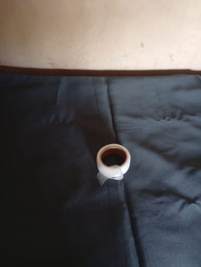 A roll of white tape, partially wrapped in clear plastic, rests on a dark, textured surface that appears to be fabric. The background consists of a light-colored wall, possibly painted, with a darker horizontal band near the top. The scene is indoors, with the lighting suggesting it is daytime. There are no people or signs of specific activity visible. The image does not provide any specific information about its location in Gulak, Nigeria.