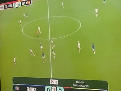 The image shows a soccer match displayed on a screen. The scoreboard at the top indicates the time is 3:30, with France (FRA) having 0 points and Spain (ESP) having 2 points. The scoreboard at the bottom shows the time as 75:30, with the names "PORRO 58'" and "OYARZABAL 22' (P)" visible, suggesting player names and goal times. The playing field is green with white lines. Several players in white and dark uniforms are scattered across the field. There are no elements in the image that indicate the location in the city of Sredets, Bulgaria.