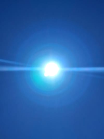 The image is a photograph of the sun with a strong lens flare effect against a clear blue sky. There are no visible people, objects, or any indication of a specific location within the city of Yeghegnadzor, Armenia. The scene is entirely focused on the atmospheric phenomenon of the sun and its interaction with the camera lens.