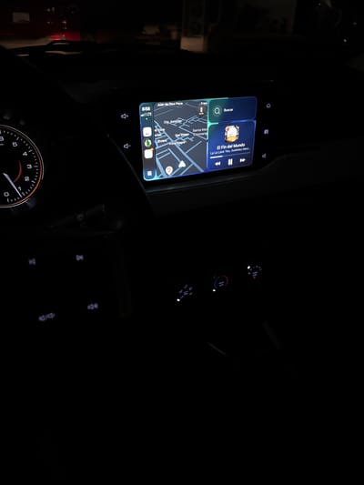 Here is a concise, forensic, matter-of-fact description of the scene:

The image shows the interior of a car at night. The dashboard screen is illuminated, displaying a map showing the location of Juan de Dios Peza, Cto. Asturias, Santa Mar, ortao, Riviera, Sao Elfego, Coronang and Vista Alegre in a location. The time displayed on the screen is 8:58, and the car is connected to LTE. The car is in park at 0 km/h. The dashboard screen is also displaying the song "El Fin del Mundo" by La La Love You, Axolotes Mexicanos. The steering wheel and a dimly lit speedometer are visible. The controls for the car's climate control system are also illuminated.