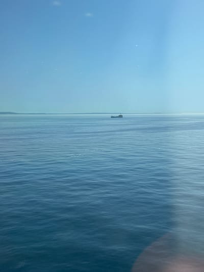The image shows a body of water, likely the sea, with a small structure visible in the distance. The sky is overcast and blue-gray. The water is choppy, with noticeable wave patterns. The location is unknown, France. No people are visible. The object is the structure in the water, possibly a platform or buoy. No actions or interactions are observable. The environment is marine, with a cloudy sky.