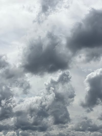 This is a close-up, high-angle shot of a cloudy sky. The clouds are predominantly gray with some lighter white areas, suggesting an overcast or potentially stormy day. There is a small, dark silhouette of a bird flying in the lower left quadrant of the image. The image appears to be an outdoor scene, with no discernible urban elements, making it impossible to determine if it is located in Beşiktaş, Turkey.
