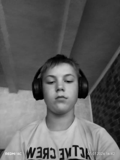 A black and white, head-on, close-up, selfie-style, waist-up shot of a young person wearing headphones and a t-shirt. The person is looking directly at the camera with a neutral expression. The background consists of a textured wall and what appears to be a brick wall. The bottom left corner of the image displays "REDMI 14C", and the bottom right corner shows the date and time "01.07.2026 16:42". The image is undated and therefore cannot be associated with a specific location in Pepeni, Moldova, or any other city.