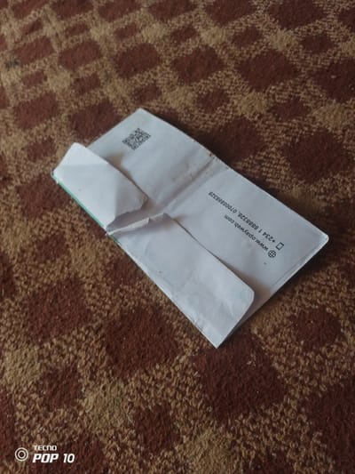 An open white envelope lies on a brown and tan checkered carpet. A QR code is printed on the top left corner of the envelope's interior. On the right side of the interior, text is printed vertically: "www.opayweb.com +234 1 8888328, 0708888328". A small globe icon is printed to the left of the phone number. The Tecno Pop 10 logo is visible in the bottom left corner of the image. The scene is indoors in Gulak, Nigeria.
