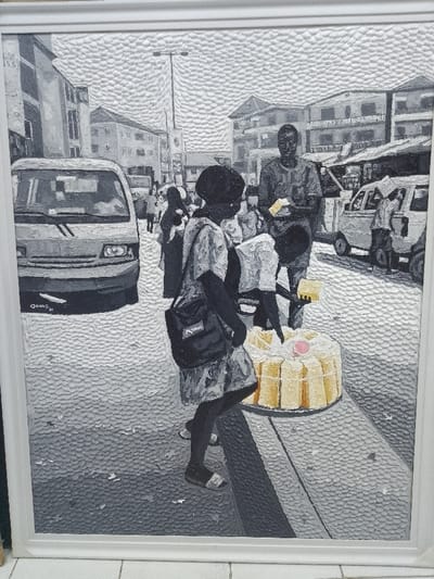 The image is a framed, textured oil painting depicting a street market scene in Ikate, Nigeria. The artwork is predominantly grayscale with vibrant yellow and a singular pink detail.
In the foreground, a Black woman walks towards the right side of the frame, her head slightly turned towards her left (viewer's right). She wears a light-colored patterned dress, dark sandals, and a dark cross-body shoulder bag. Immediately to her right, on a gray raised curb, a large round cake display is visible. This display features a light-colored, possibly white, base encircled by numerous vertical, rectangular yellow cake slices. A small pink circular decoration sits atop the center of the large base.
Behind the foreground woman and the cake display, a Black male vendor stands, facing the viewer, holding a small rectangular yellow item in each hand, consistent with a food product offered for sale. Another partially obscured figure is visible near the cake display.
The background depicts a bustling urban environment. Multi-story buildings, rendered in various shades of gray, line both sides of the street. Informal market stalls or structures are visible on the right side. Two light-colored vans are present: one prominently positioned on the far left foreground, displaying the artist's signature "OJIBE '23" near its front bumper, and another on the right mid-ground. A tall street lamp post is centrally located in the background. Both the street pavement and the sky exhibit a pronounced impasto texture.