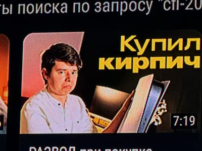 The image shows a screenshot of a video on a screen. At the top of the screen, white text reads "ты поиска по запросу 'sti-20". In the center of the screen, on the left, a young person with dark hair is wearing a white collared shirt. Their face is looking down with a slightly worried or sad expression. To the right of the person, large yellow text reads "КУПИЛ КИРПИЧ". The background behind the text is black. There is also a visual element that appears to be a stack of files or books with some light reflecting off them. In the bottom right corner of the screen, a black box displays the time "7:19". The image quality is slightly distorted due to the screen's display, showing vertical lines. There is no indication of the location being Castillo Bajo-conejito, Spain.