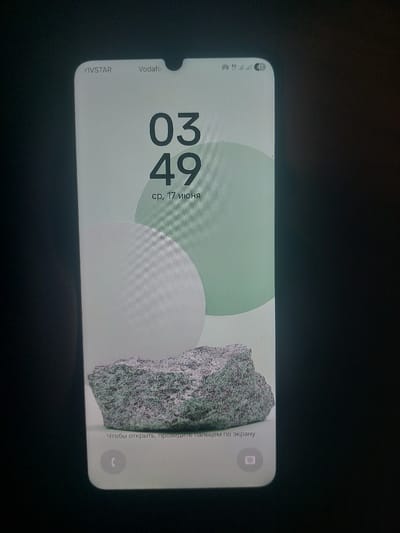 The image shows a smartphone screen displaying a lock screen. The phone is held vertically, and the background features abstract shapes in pastel green and white, with a textured stone in the foreground. The time displayed is 03:49, and the date is Wednesday, June 17th. At the top of the screen, "YIVSTAR" and "Vodafone" are visible, along with signal strength indicators and a battery icon. A notification icon with the number "41" is present in the top right corner. At the bottom of the screen, there is text in Russian that translates to "To unlock, swipe your finger across the screen" and icons for a phone and a camera. The device is black and has a notch at the top. The overall scene is a close-up of a smartphone interface, with no visible context of its location in the city of Korolevo, Ukraine.