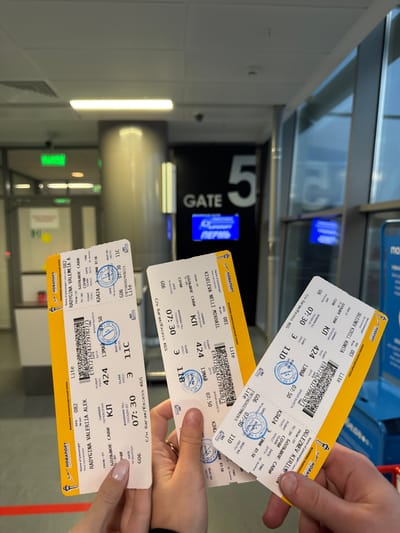 The image shows three boarding passes for Novaport airlines. One is for Ogleznev Kirill Konsta, flight KL 424 from Bolshoye Savino to Sochi, departing May 13th at 07:50, seat 11D, gate G06, Boarding time 07:30. Another is for Kiseleva Nelli Mikhail, flight KL 424 from Bolshoye Savino to Sochi, departing May 13th at 07:50, seat 11B, gate G06, Boarding time 07:30. The last is for Radygina Valeria Alek, flight KL 424 from Bolshoye Savino to Sochi, departing May 13th at 07:50, seat 11C, gate G06, Boarding time 07:30. The boarding passes are being held by hands with manicured nails. Background shows "Gate 5". The location is likely an airport. There is no information on the city of Boldino, Russia.
