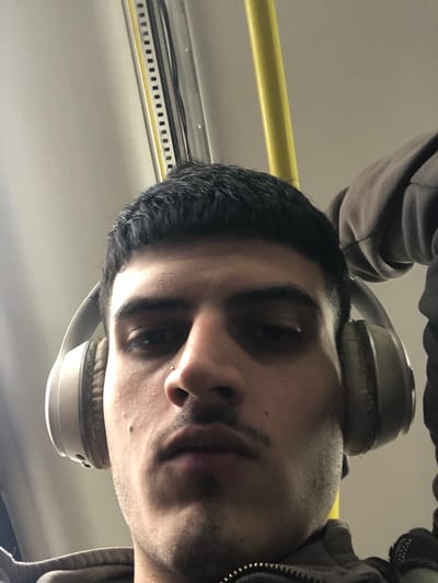 A close-up, angled shot depicts a person wearing headphones. The individual has dark hair and appears to be on a train or bus, suggested by a yellow handrail and overhead infrastructure. No information in the image allows for identification of the location as San Isidro, Argentina.