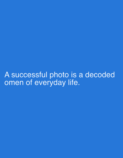 The image is a photograph with a solid blue background. White text is overlaid on the image, reading: "A successful photo is a decoded omen of everyday life." There are no people, subjects, objects, actions, interactions, or environmental details visible beyond the text and background. The image does not depict any location in Even Yehuda, Israel.