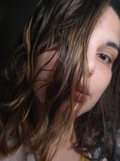 The image depicts a close-up view of a person's face, angled to the side. The person has brown hair with some lighter highlights, which obscures a portion of the face. Only one eye is fully visible; it's brown. Part of the nose and mouth are also visible. The skin tone appears light. No information about the city of Амзя, Russia, or any environmental details is present in the image.