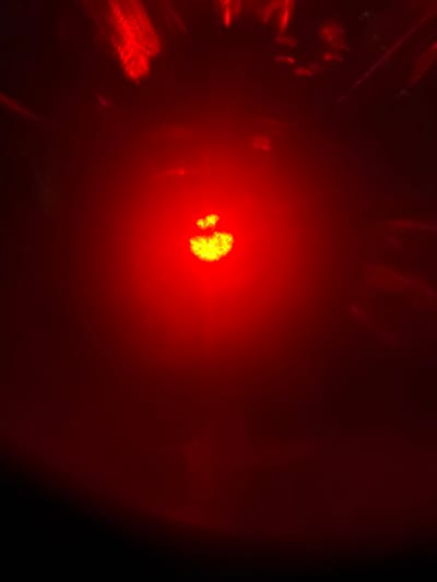 The image shows a blurred, abstract red light with a bright, fuzzy yellow-green center. Streaks and patterns of red light are visible in the background, suggesting a dynamic light source or reflections. The overall impression is one of intense, diffused light against a dark background. There are no discernible objects, people, or environmental features that can be identified as being located in Branipole, Bulgaria, or any other specific location.