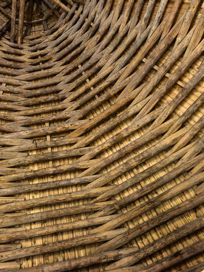 The image shows the interior roof structure of a building, likely a historical one, constructed from natural materials. The roof is made of interwoven branches and wooden logs, creating a rustic and organic pattern. The underlying structure appears to be composed of smaller, lighter-colored wooden planks or reeds. The overall impression is one of traditional craftsmanship and natural materials. The image does not contain any people or explicit actions. It is a close-up view, focusing on the texture and construction of the roof. The location in Staraya Ladoga, Russia, suggests a historical context, possibly relating to a monastery, church, or ancient dwelling.