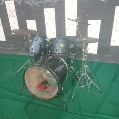 A drum set sits on a stage. The left side of the stage has a black and white design. The right side has green carpet. The location is Duaca, Venezuela.