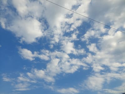 The image shows a sky with scattered white clouds against a bright blue backdrop. A thin black wire diagonally traverses the upper portion of the frame from left to right. The clouds vary in density, with some appearing wispy and others more voluminous. The overall impression is of a partly cloudy day. The provided information about the image's location in Markovo, Bulgaria, is not visually discernible from the image itself, as there are no geographical landmarks or distinctive features to indicate this specific place.