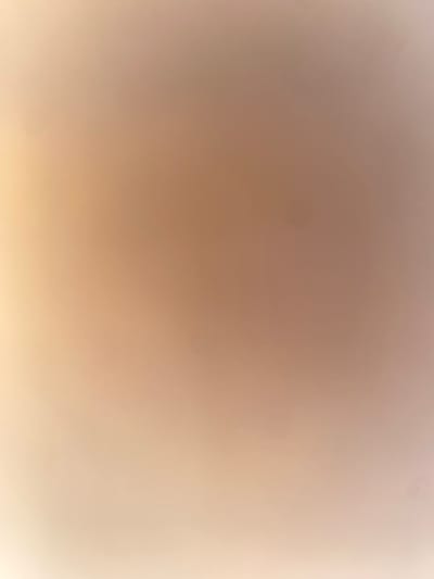The image is a close-up, slightly out-of-focus shot of a wall. The wall appears to be painted in a gradient of light peach and beige tones, with some subtle darker spots visible, possibly dust or imperfections in the paint. There are no people, objects, or discernible features that would suggest a specific location within the city of Ablanitsa, Bulgaria, or any other identifiable environment. The lighting is soft and diffused, creating a smooth, almost abstract appearance.