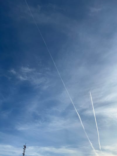 The image shows a blue sky with wispy clouds and contrails from aircraft. A crane is visible in the lower right corner. It is impossible to confirm the location as Uray, Russia, without additional information.