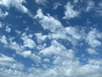 The image shows a blue sky with scattered white clouds. The clouds vary in size and shape, with some appearing fluffy and others more wispy. The sky is a clear, vibrant blue. The bottom of the image suggests the presence of more clouds, likely low-lying or near the horizon. There is no indication of the location being Chituk, Russia, or any other specific place. There are no people, subjects, objects, actions, or interactions visible in the image, except for the clouds in the sky. The environment is solely the sky.
