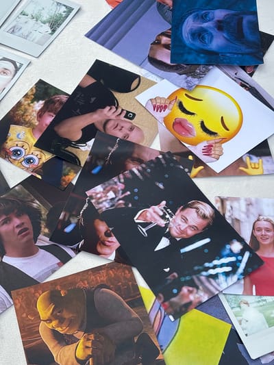 The image displays a collection of scattered photographs on a textured surface. The photographs are of varying sizes and orientations, creating a layered and somewhat chaotic composition.

Visible in the photographs are:

*   A group of people dressed in formal attire, possibly at an event.
*   A person's face with eyes looking upwards and a beard, rendered in a blue-toned light.
*   A close-up of a person's face with a concerned expression, a portion of a Spongebob Squarepants-themed shirt visible.
*   A person holding a smartphone.
*   A large yellow emoji with its tongue sticking out, accompanied by manicured red fingernails.
*   A hand making a "rock on" gesture.
*   A person in a tuxedo holding a glass of champagne, identified as Leonardo DiCaprio.
*   A young woman with long hair smiling.
*   A photograph of the character Shrek.
*   A photograph of a woman in a white dress in an outdoor setting.
*   Other partially visible photographs with abstract patterns and colors.

The surface appears to be a light-colored, textured material, possibly a tabletop or a similar flat surface. The lighting is natural, casting subtle shadows.

There is no information within the image or its context that indicates a location in the city of Osipovo, Russia.